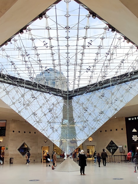 Inverted Pyramid inside Louvre Museum with visitors exploring the area.