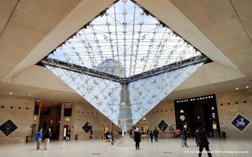 Inverted Pyramid inside Louvre Museum with visitors exploring the area.