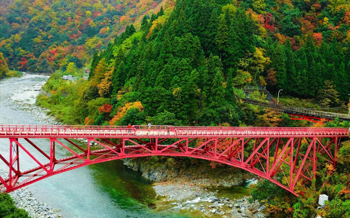 Yamabiko Red Bridge over mountain river in Kurobe Gorge, Toyama, Japan during autumn.