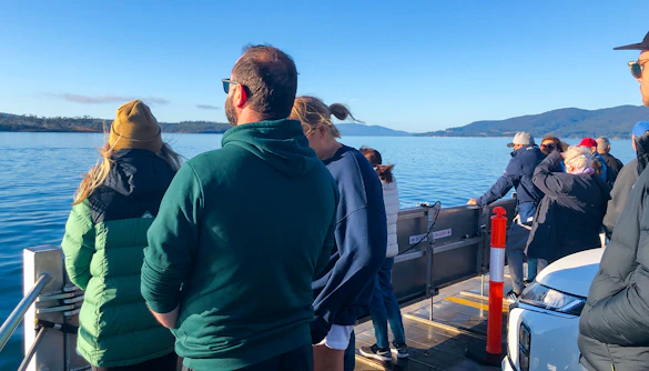 Tourists on a boat enjoying views of Bruny Island's coastline from Hobart.