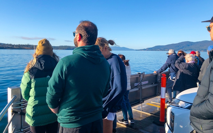 Tourists on a boat enjoying views of Bruny Island's coastline from Hobart.