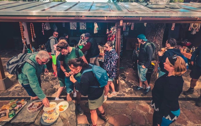 Tourists sampling local food at a market stall during Gran Canaria volcano sunset tour.