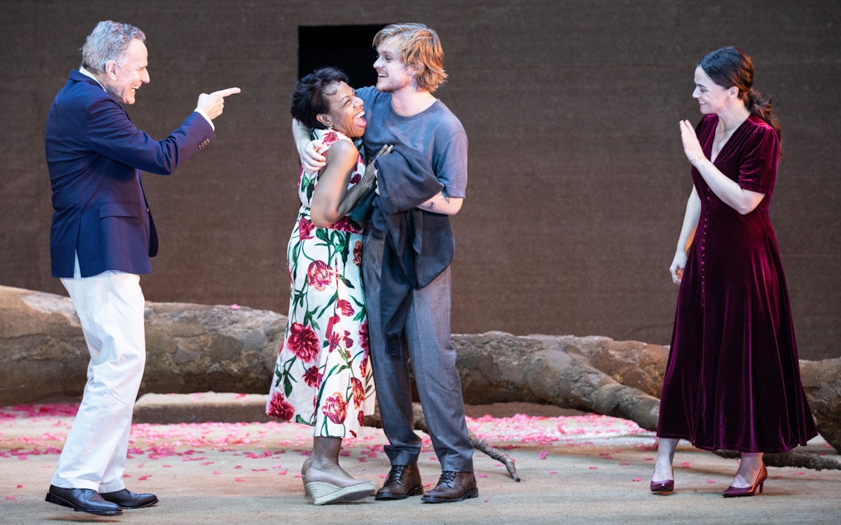 Actors performing on stage in the West End show "All My Sons" with a backdrop of fallen tree branches.