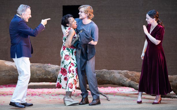 Actors performing on stage in the West End show "All My Sons" with a backdrop of fallen tree branches.