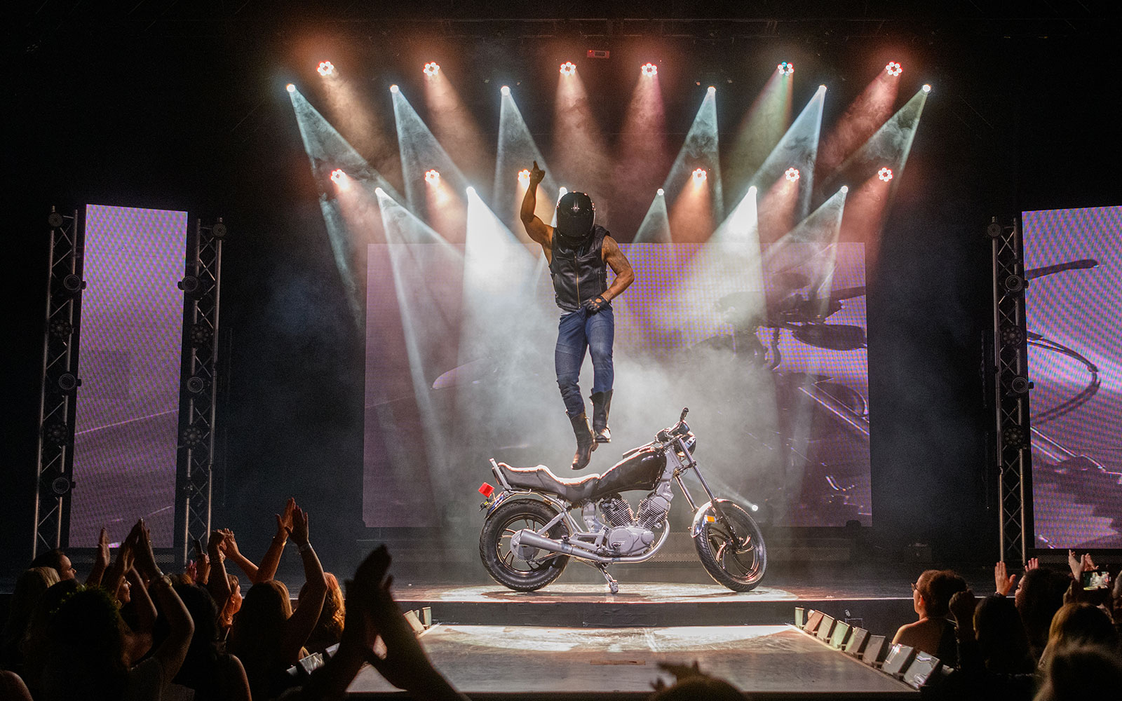 Performer jumping on stage with motorcycle during Chippendales act.