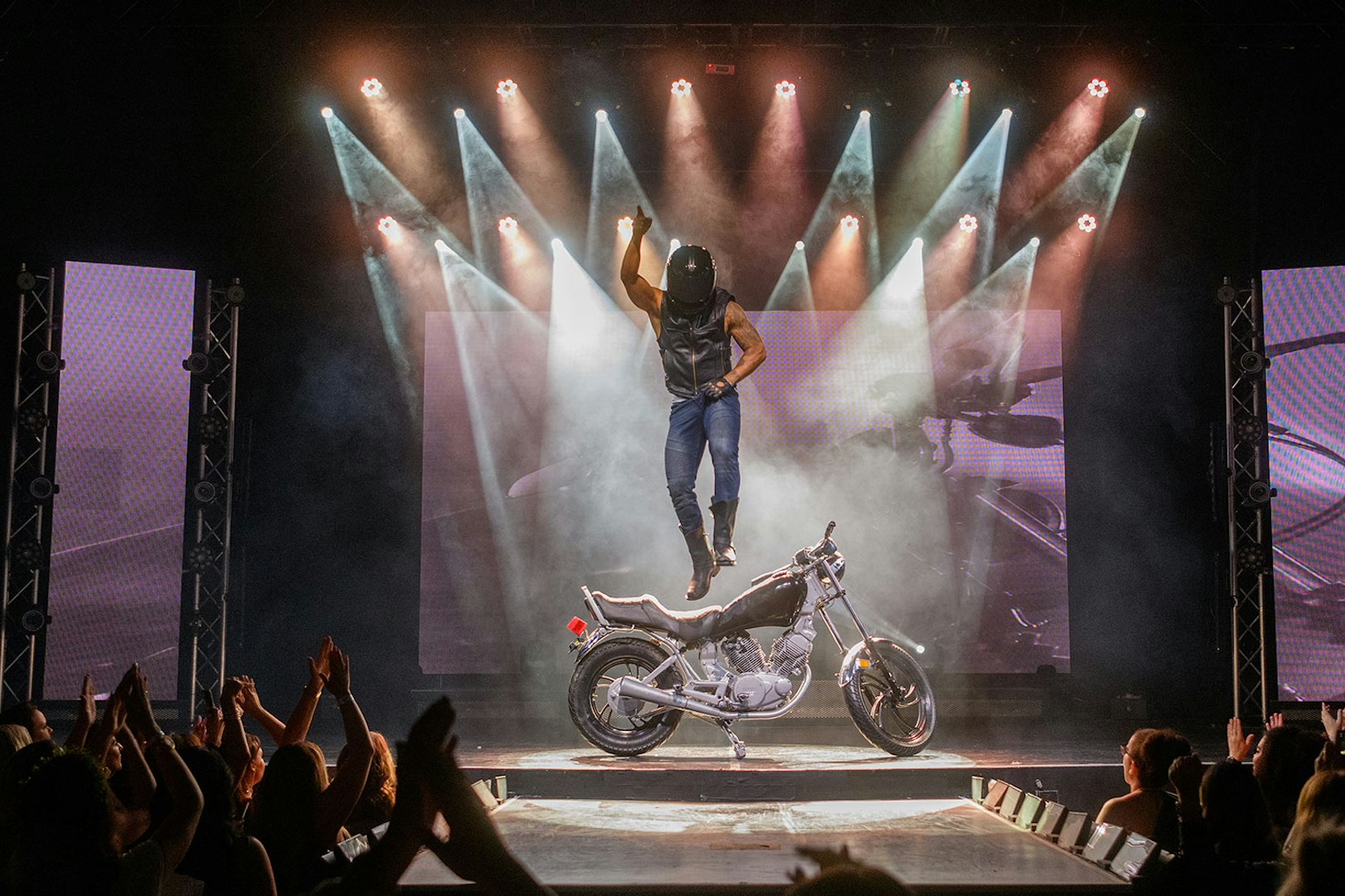 Performer jumping on stage with motorcycle during Chippendales act.