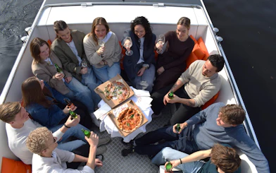 Group enjoying Nolita pizza and drinks on a Haarlem canal dinner cruise.