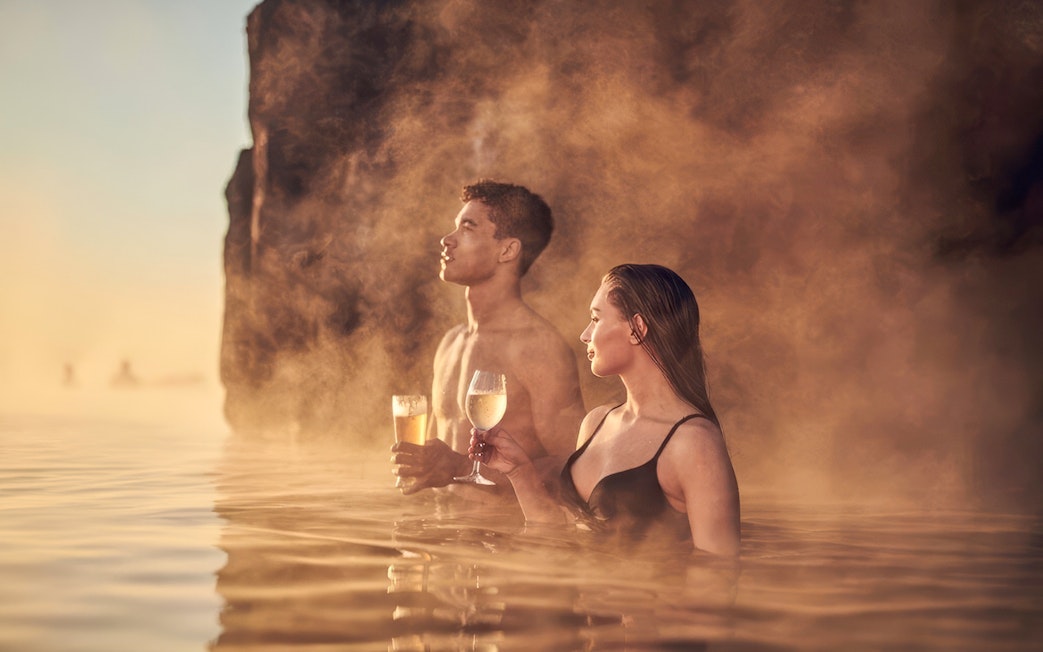 Guests enjoying drinks in the warm waters of Sky Lagoon.