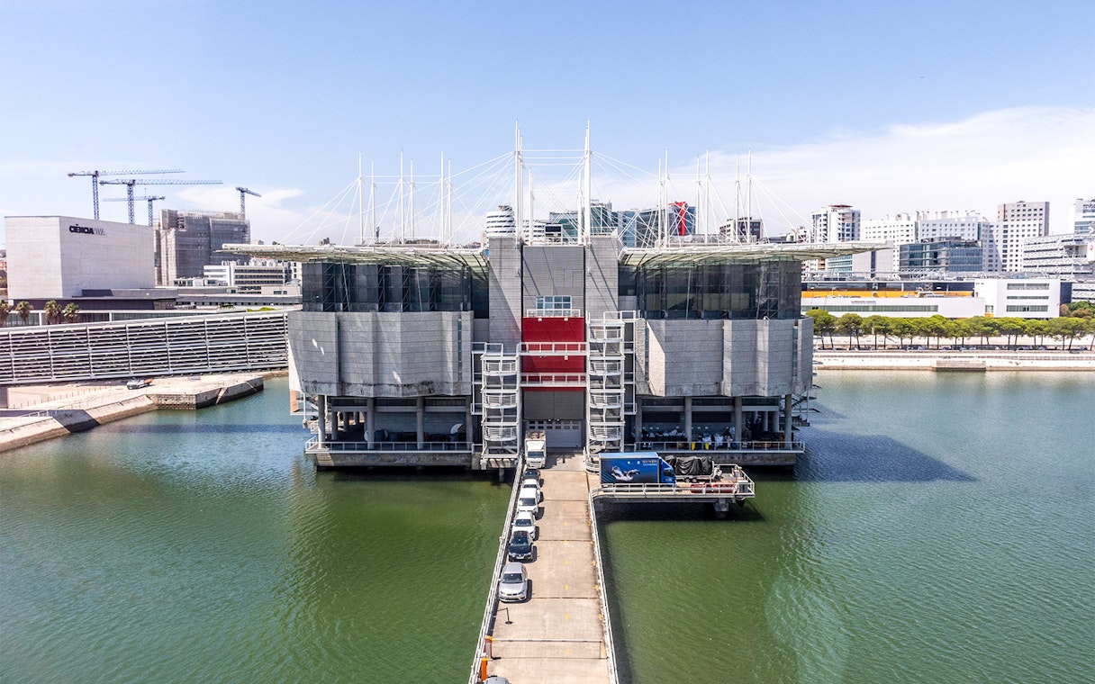 Lisbon Oceanarium building surrounded by water with cityscape in the background.