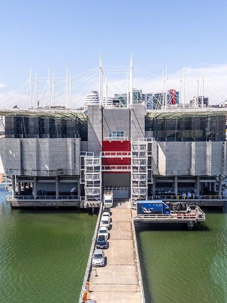 Lisbon Oceanarium building surrounded by water with cityscape in the background.