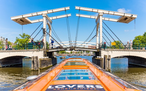 Amsterdam canal cruise boat approaching Magere Brug bridge.