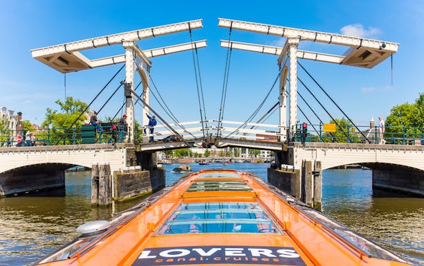 Amsterdam canal cruise boat approaching Magere Brug bridge.