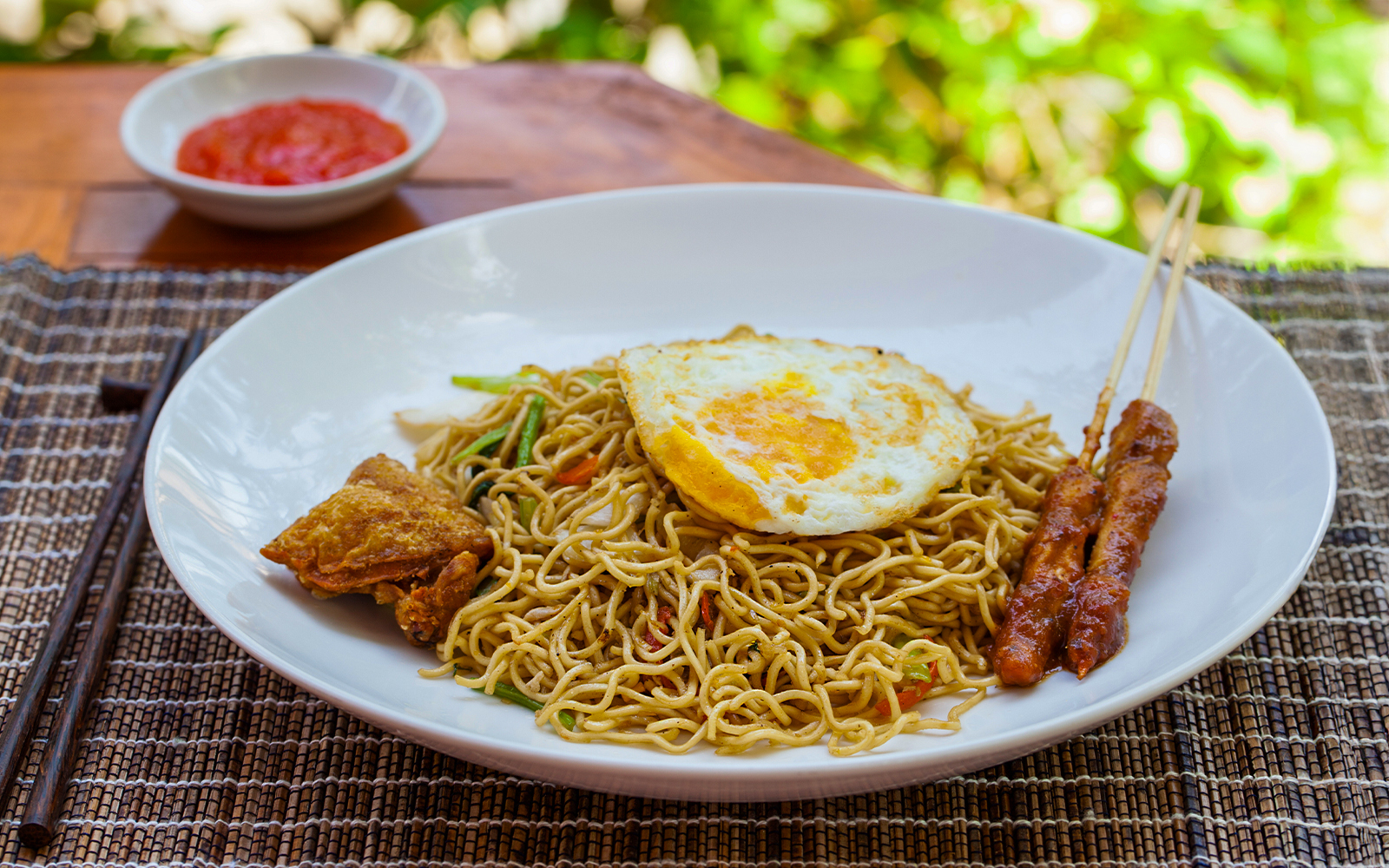 Nasi goreng with fried egg, satay skewers, and sambal, Ubud tour meal option.