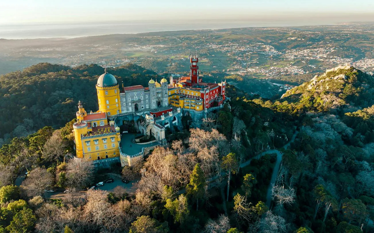 Aerial view of Pena Palace in Sintra, surrounded by lush forest, part of a private tour with Moorish Castle tickets.