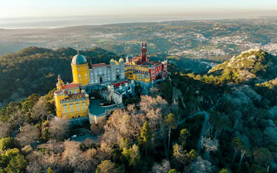 Aerial view of Pena Palace in Sintra, surrounded by lush forest, part of a private tour with Moorish Castle tickets.