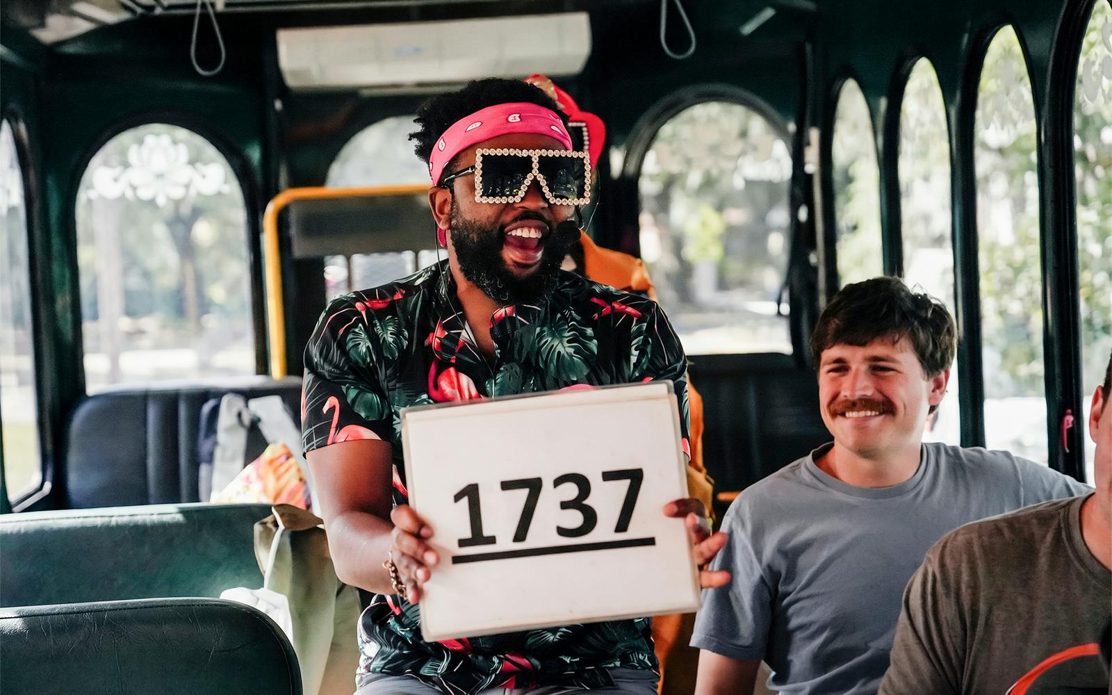 Tour guide holding a sign with "1737" on the Nashville For Morons Comedy Trolley Tour.