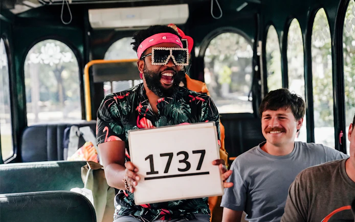 Tour guide holding a sign with "1737" on the Nashville For Morons Comedy Trolley Tour.