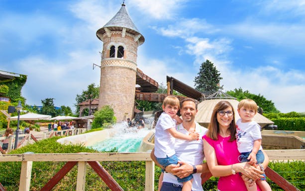 Family enjoying a day at Leolandia with a water ride and tower in the background.