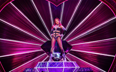 Performer on stage at Moulin Rouge! The Musical, West End, with vibrant pink lighting.