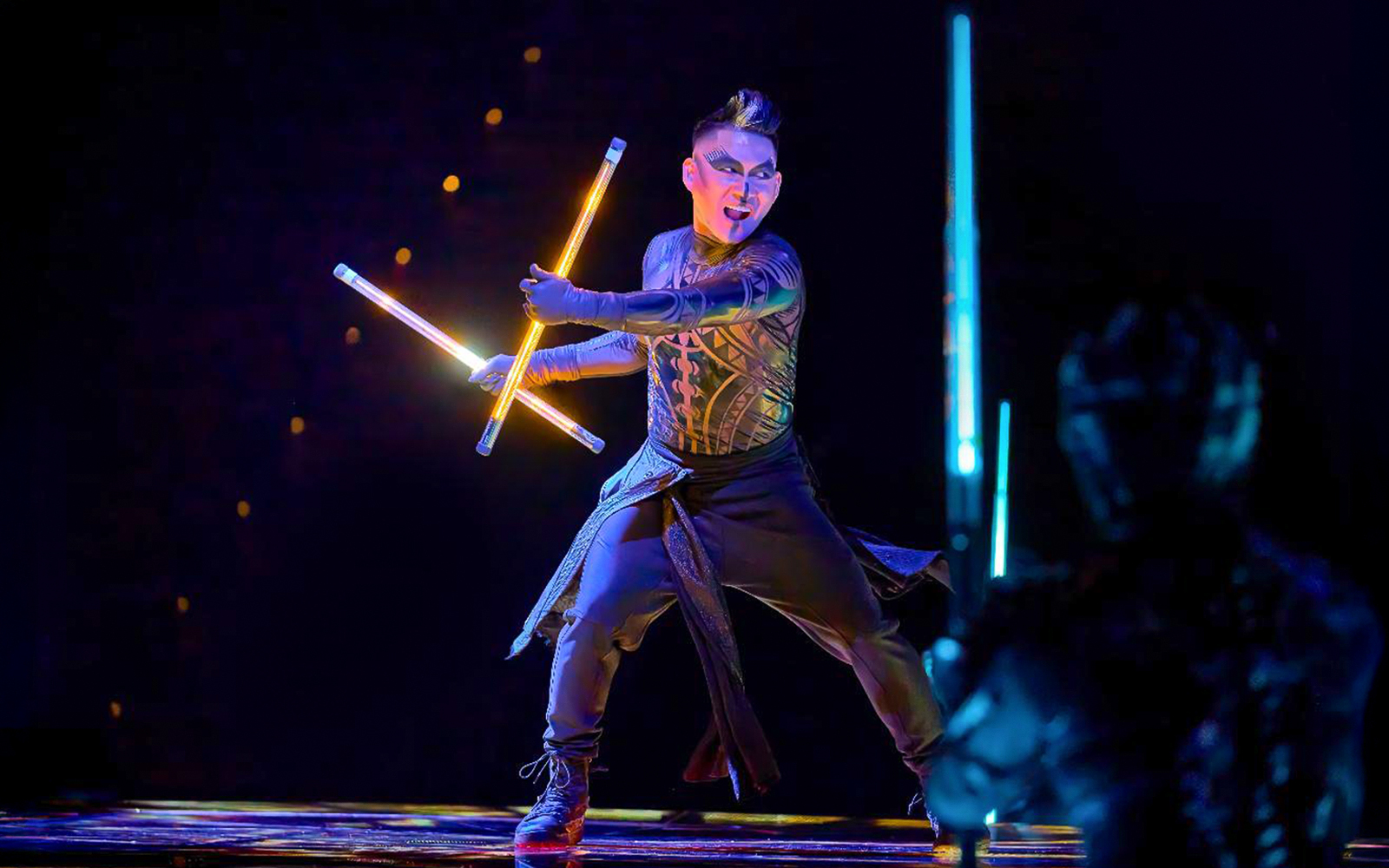 Performer with glowing batons on stage during Awakening show.