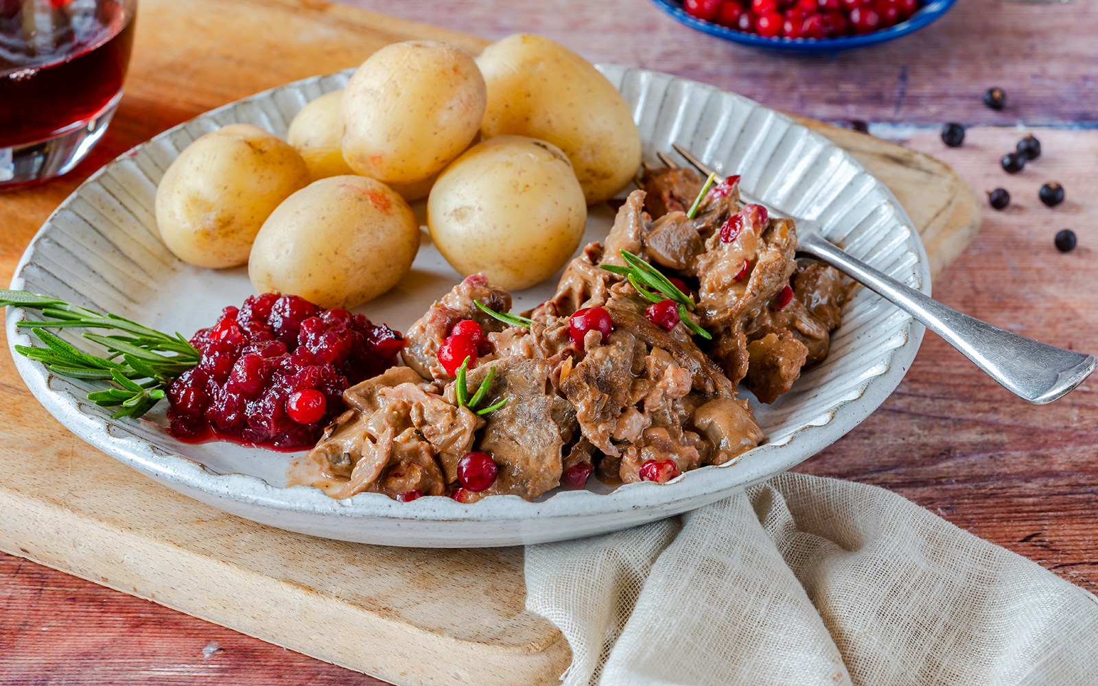 Traditional Norwegian reindeer stew with lingonberries and potatoes on a plate.