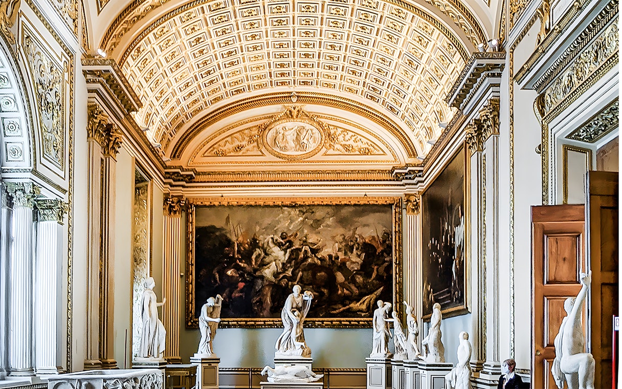 Uffizi Gallery interior with classical sculptures and ornate ceiling in Florence, Italy.
