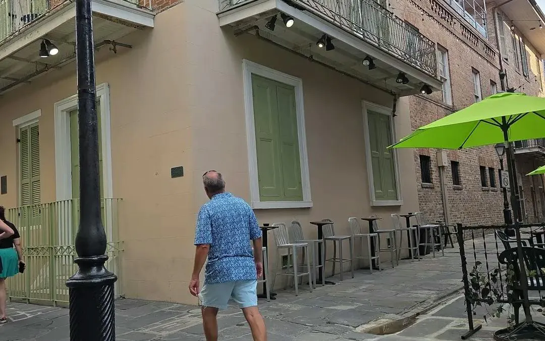 Man walking past a historic building with green shutters in New Orleans.
