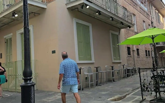 Man walking past a historic building with green shutters in New Orleans.
