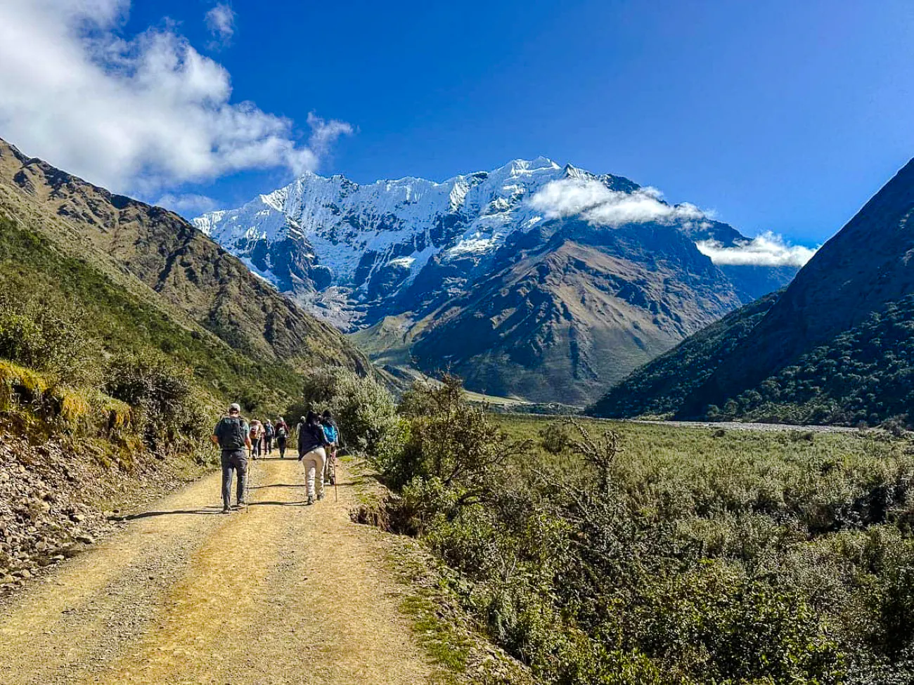 Hikers on a trail towards Humantay Lake with snow-capped mountains in Cusco.