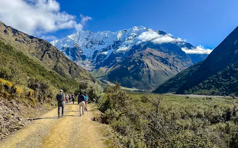 Hikers on a trail towards Humantay Lake with snow-capped mountains in Cusco.