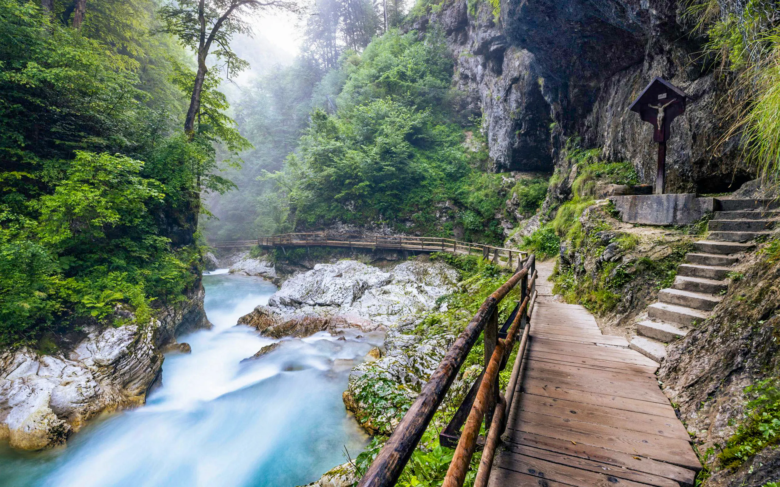 Wooden path and chapel at Vintgar Gorge, Slovenia, with flowing river and lush greenery.