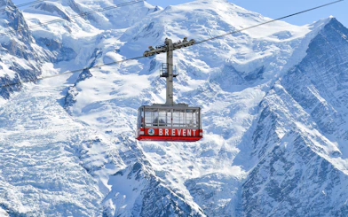Cable car ascending Mont Blanc with snowy peaks in Chamonix, France.