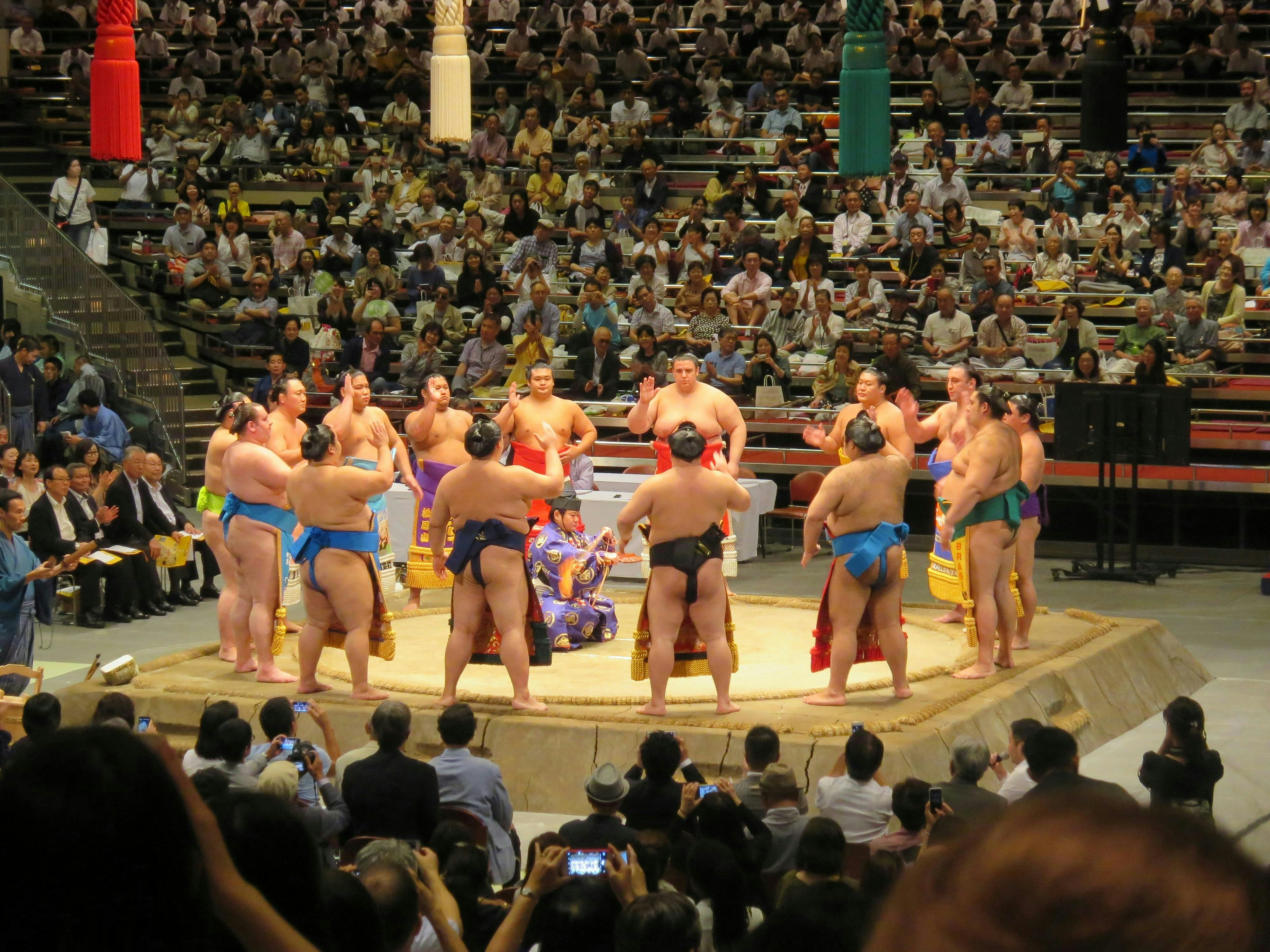 Sumo wrestlers in a Tokyo ring with a large crowd watching.