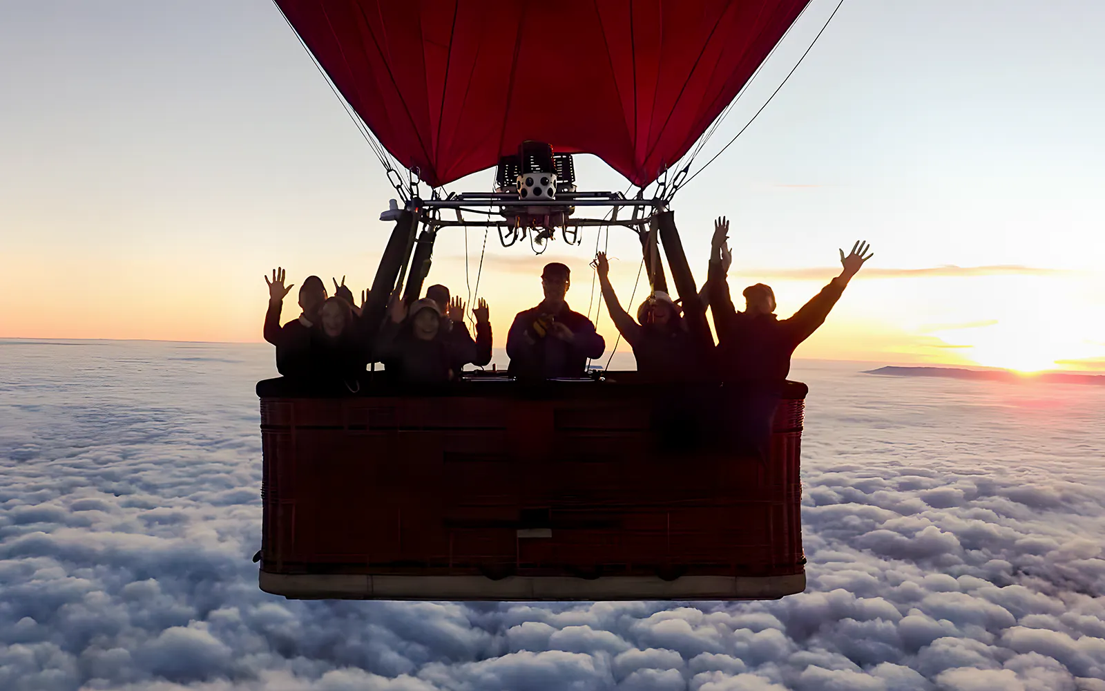 Hot air balloon with passengers over Melbourne skyline at sunrise.