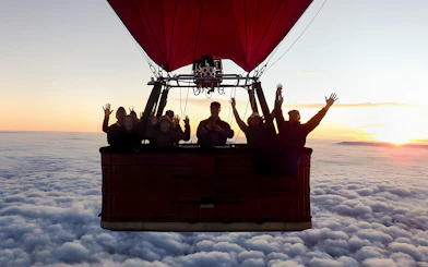 Hot air balloon with passengers over Melbourne skyline at sunrise.