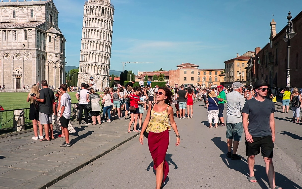 Tourists exploring Piazza dei Miracoli with the Leaning Tower of Pisa in the background.