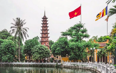 Tran Quoc Pagoda by the lake in Hanoi with Vietnamese flag.