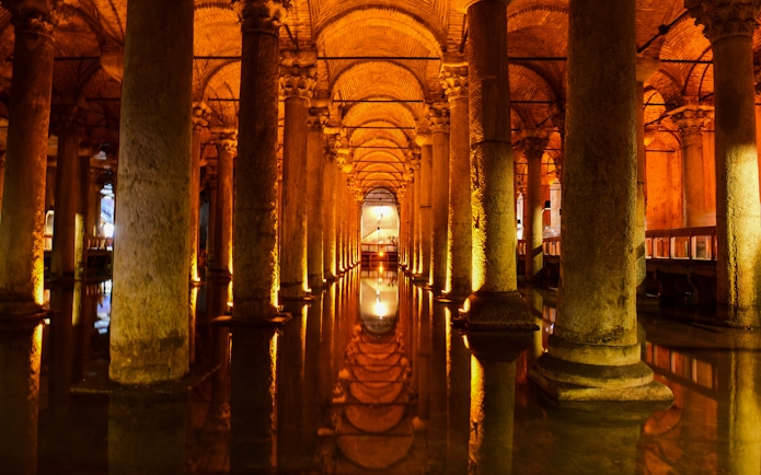 Columns inside Basilica Cistern, Istanbul, reflecting in illuminated water.