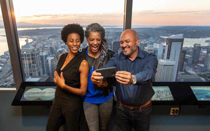 Guests taking a selfie with Seattle skyline at SkyView Observatory.