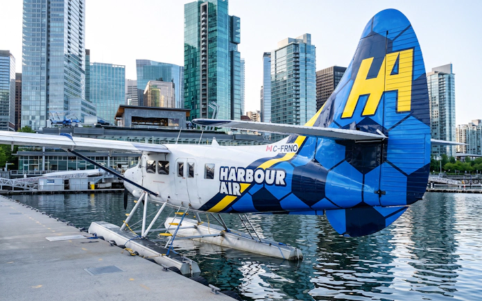 Seaplane docked in Vancouver harbor with city skyline in background.