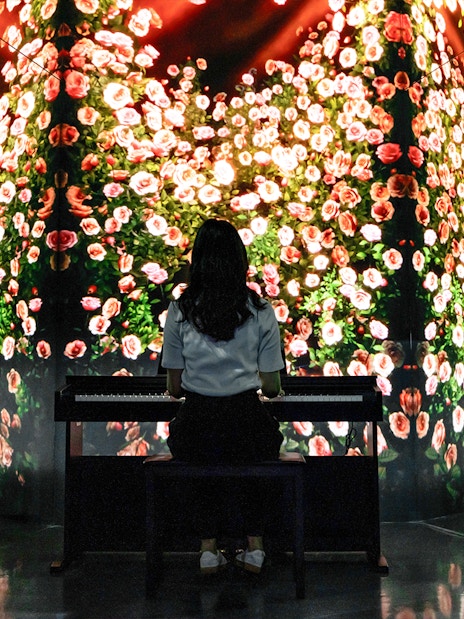 Woman at piano with rose art installation in Arte Museum Dubai.