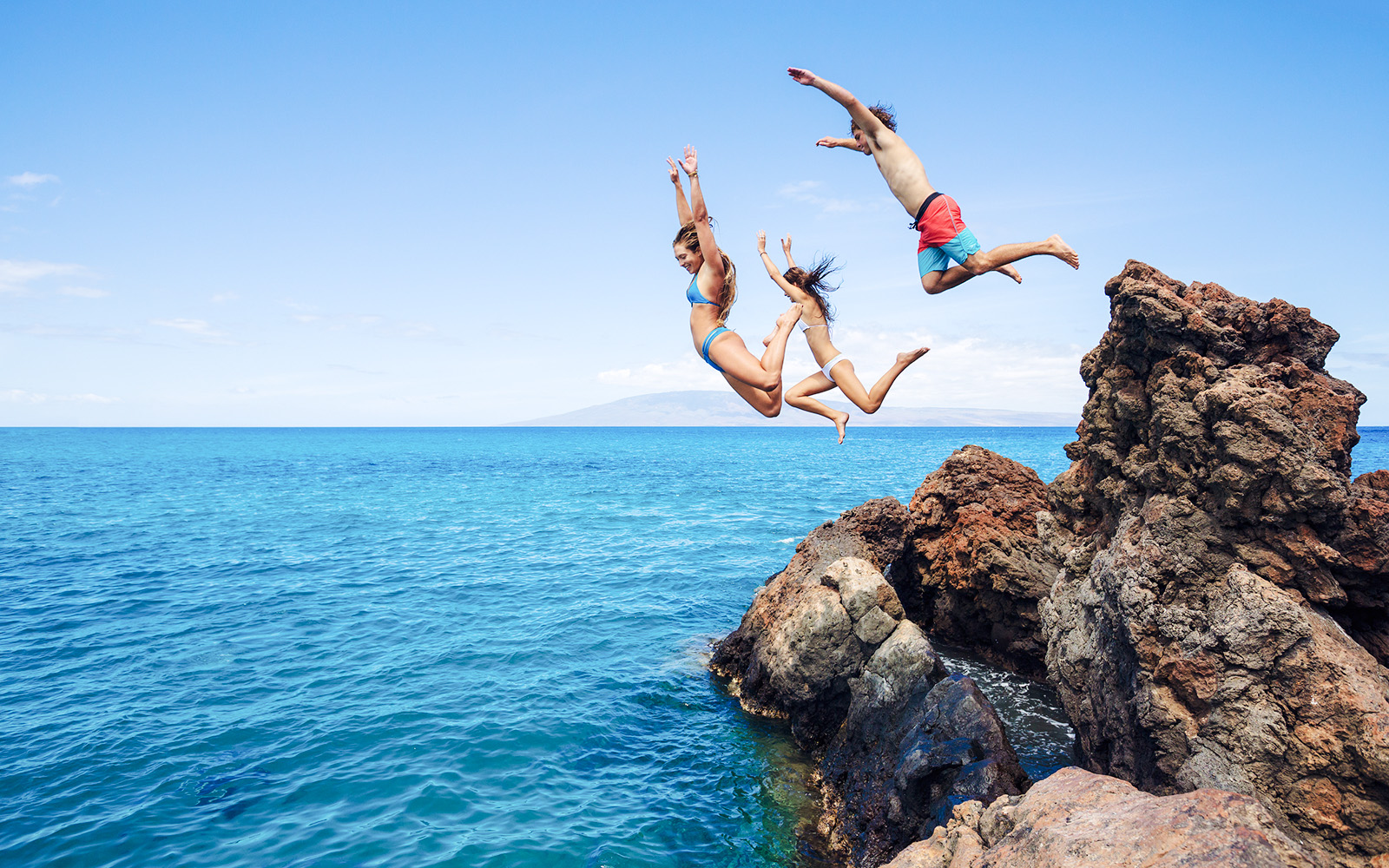 People cliff jumping into the ocean along the Road to Hana, Maui, Hawaii.
