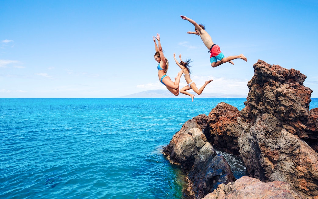 People cliff jumping into the ocean along the Road to Hana, Maui, Hawaii.