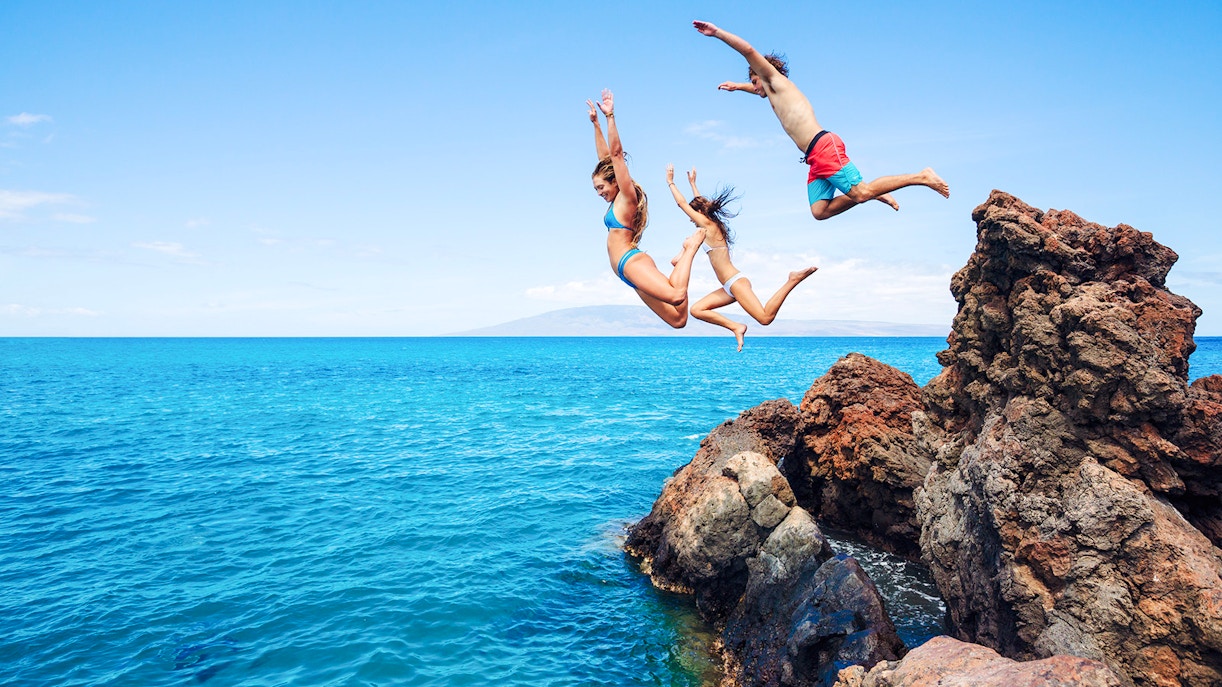 People cliff jumping into the ocean along the Road to Hana, Maui, Hawaii.