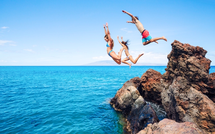 People cliff jumping into the ocean along the Road to Hana, Maui, Hawaii.