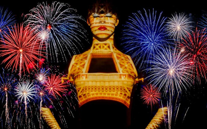 Fireworks over Paris with Eiffel Tower projection during Bastille Day dinner cruise.