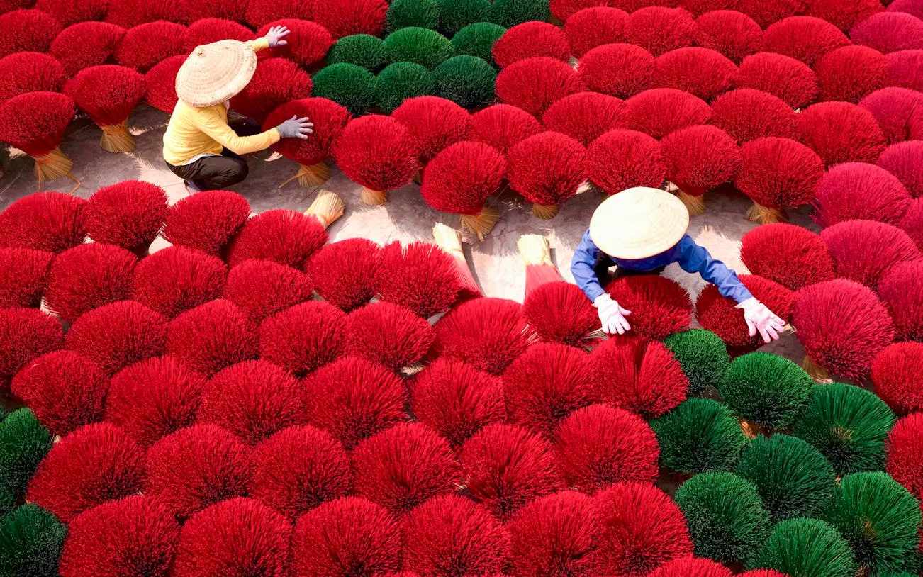 Workers arranging red and green incense sticks in a Hanoi village, Vietnam.