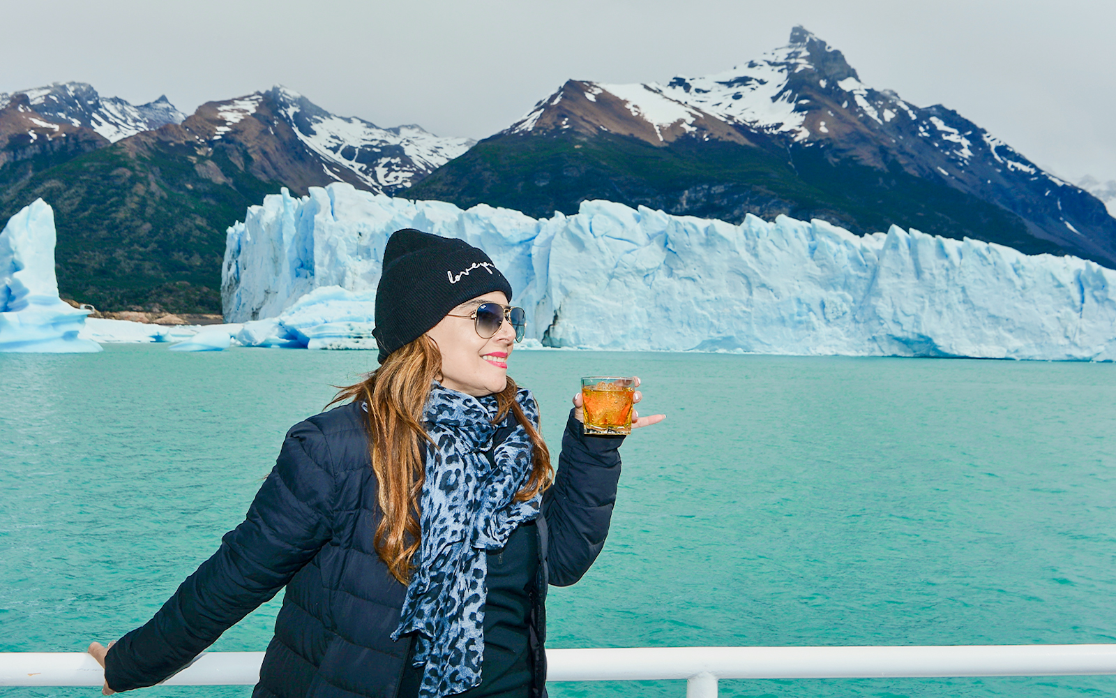 Tourist on Perito Moreno Cruise deck holding drink, viewing Perito Moreno Glacier.