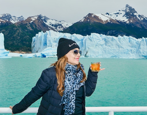 Tourist on Perito Moreno Cruise deck holding drink, viewing Perito Moreno Glacier.