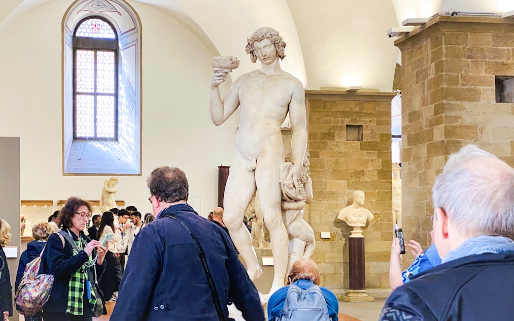 Bargello Museum visitors viewing Michelangelo's Bacchus statue in Florence, Italy.